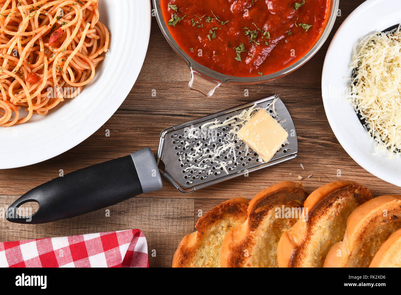 Erhöhte Ansicht einer italienischen Mahlzeit auf einem rustikalen Holz Küchentisch. Ein Teller Spaghetti, Schüssel mit Sauce, geriebener Parmesan, Stockfoto