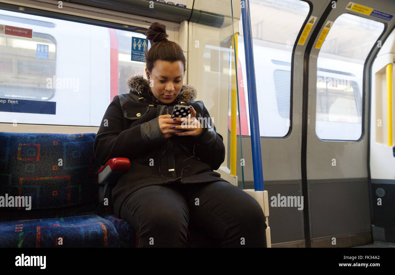 Junge Frau SMS mit dem Handy telefonieren auf die Londoner U-Bahn u-Bahn London UK Stockfoto