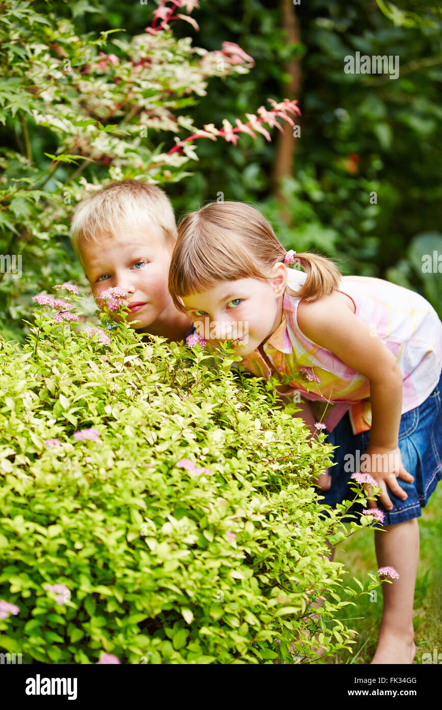 Zwei Kinder spielen verstecken und suchen im Garten und versteckt sich