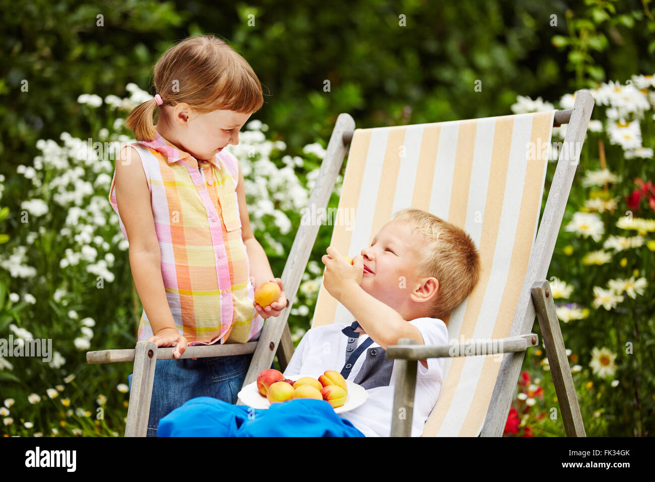 Zwei glückliche Kinder gemeinsam essen frisches Obst aus dem Garten Stockfoto