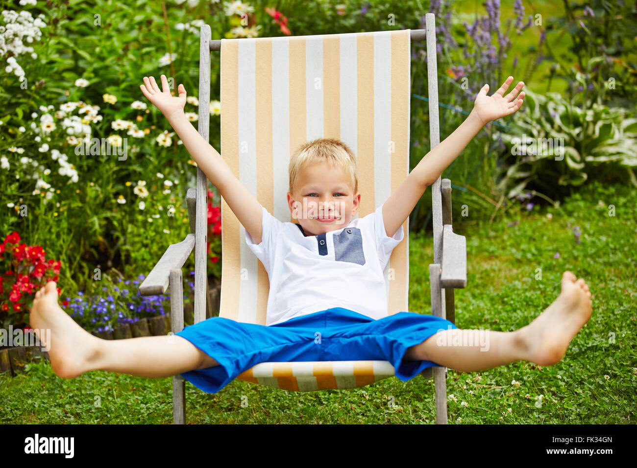 Glückliches Kind Verlegung entspannt im Liegestuhl im Sommer in einem Garten Stockfoto