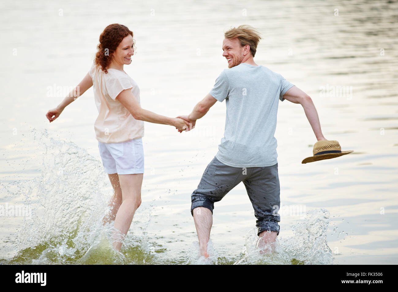 Glückliches Paar läuft durch kaltes Frischwasser im Sommer Stockfoto