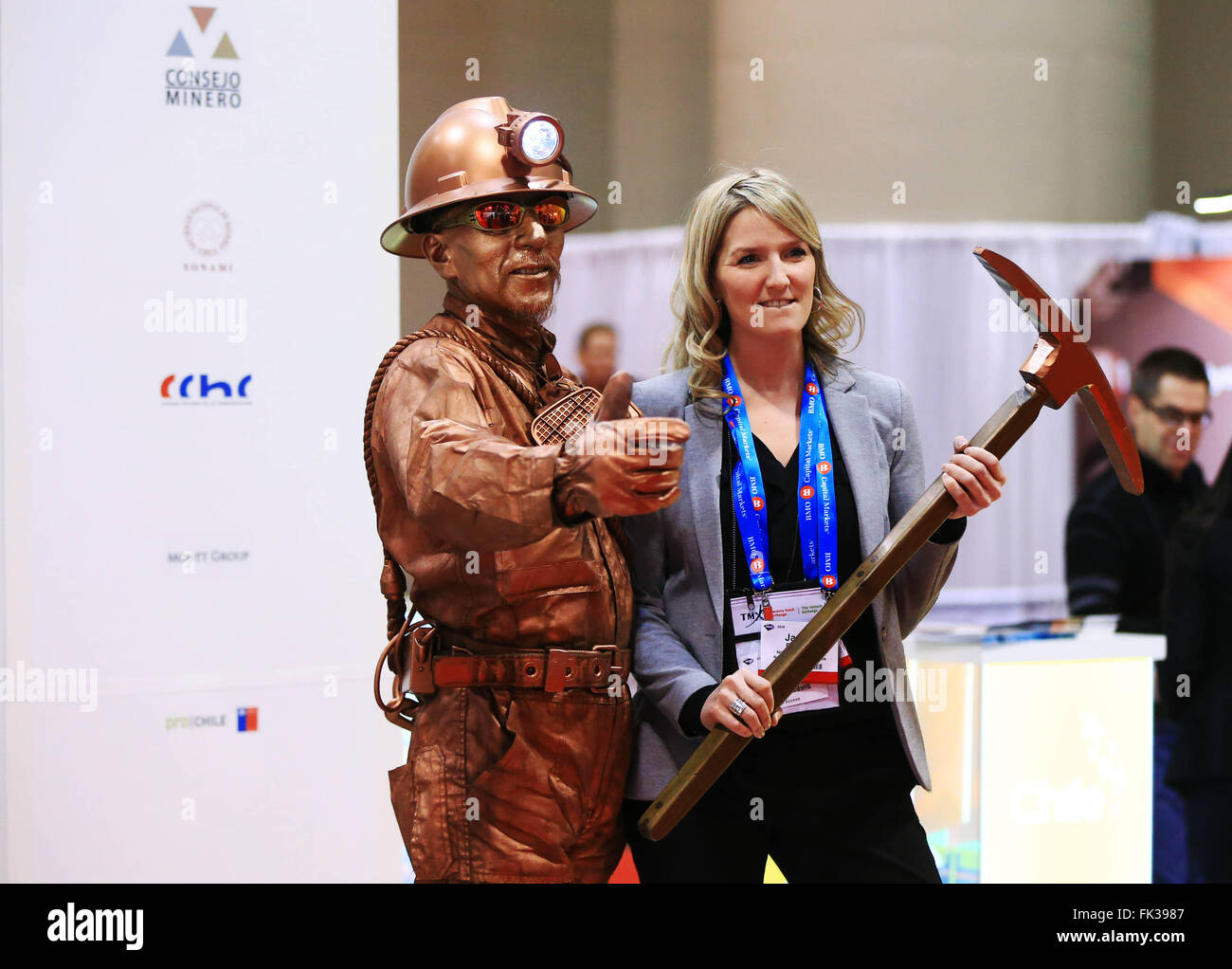 (160306)--TORONTO, 6.März, 2016(Xinhua)--Performer Danilo Parraguez-Gonzalez(L) gekleidet wie ein Bergmann Bronze Statue posiert für Fotos mit einem Teilnehmer an Chile Stand während der 2016 Goldsucher und Entwickler Association of Canada (PDAC) International Convention, Messe und Investoren Exchange-Mining Investment Show im Metro Toronto Convention Centre in Toronto, Kanada, 6. März 2016. Als eines der weltweit größten mineralischen Konferenzen der viertägigen Jahrestagung startete am Sonntag. (Xinhua/Zou Zheng) Stockfoto