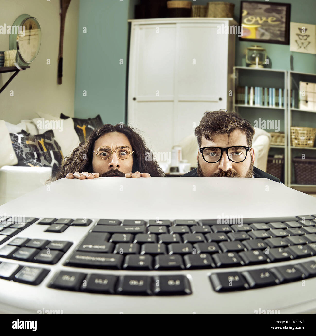 Zwei lustige IT-Spezialisten starrte auf einer Tastatur Stockfoto