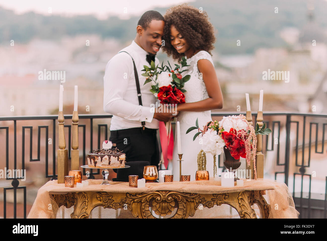 Romantische afrikanische Hochzeitspaar auf der Terrasse. Luxuriöse golden Tabelle im orientalischen Stil im Vordergrund Stockfoto