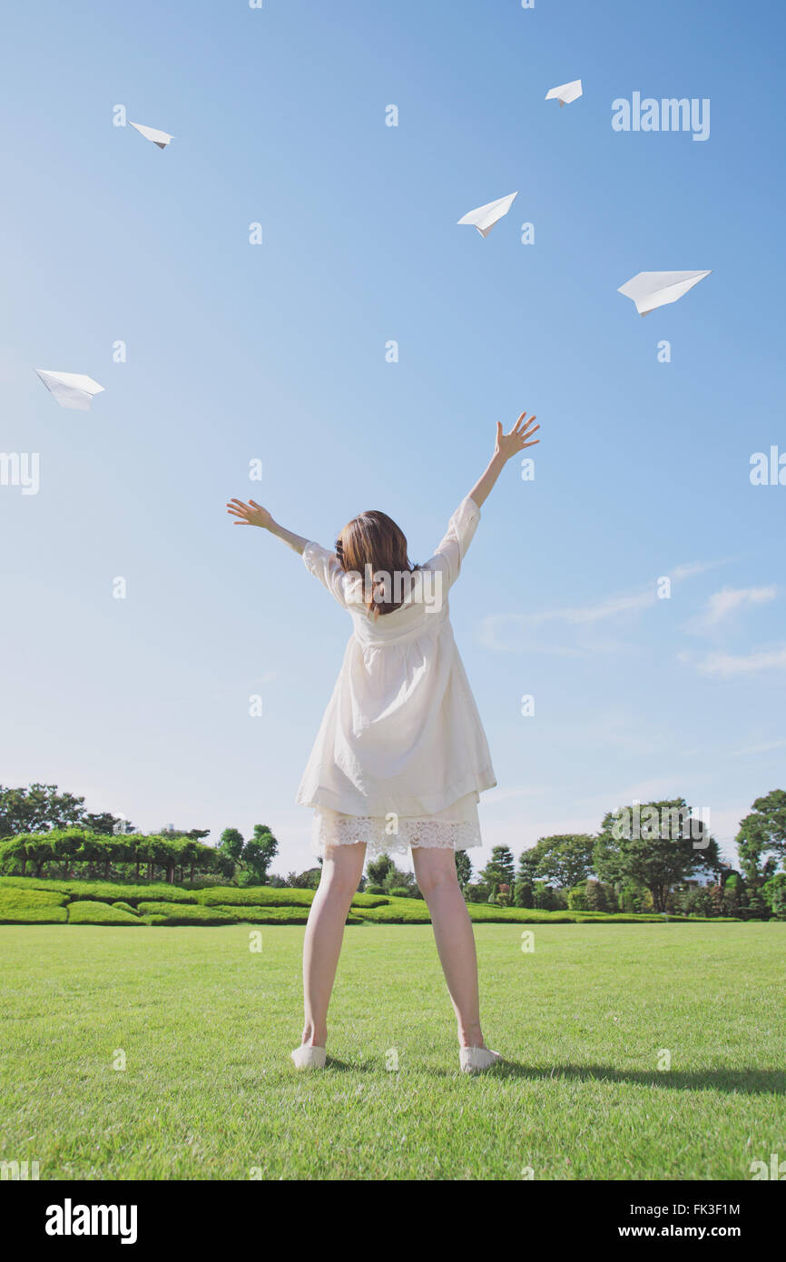 Japanische Frau fliegende Papierflieger in einem Stadtpark Stockfoto