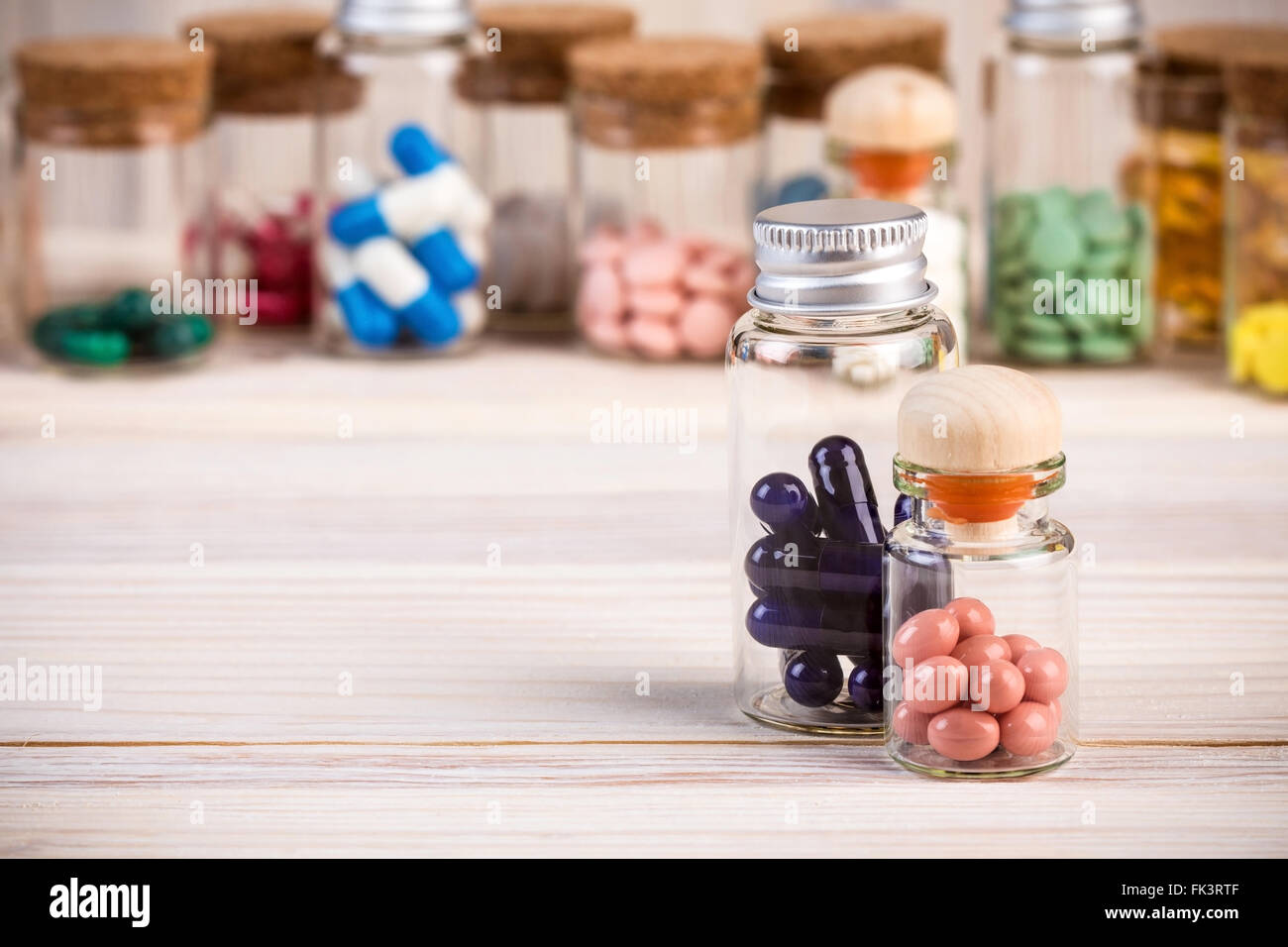 Kapseln Blau und rosa Pillen in Glasbehältern und anderen Arzneimitteln im Hintergrund Stockfoto