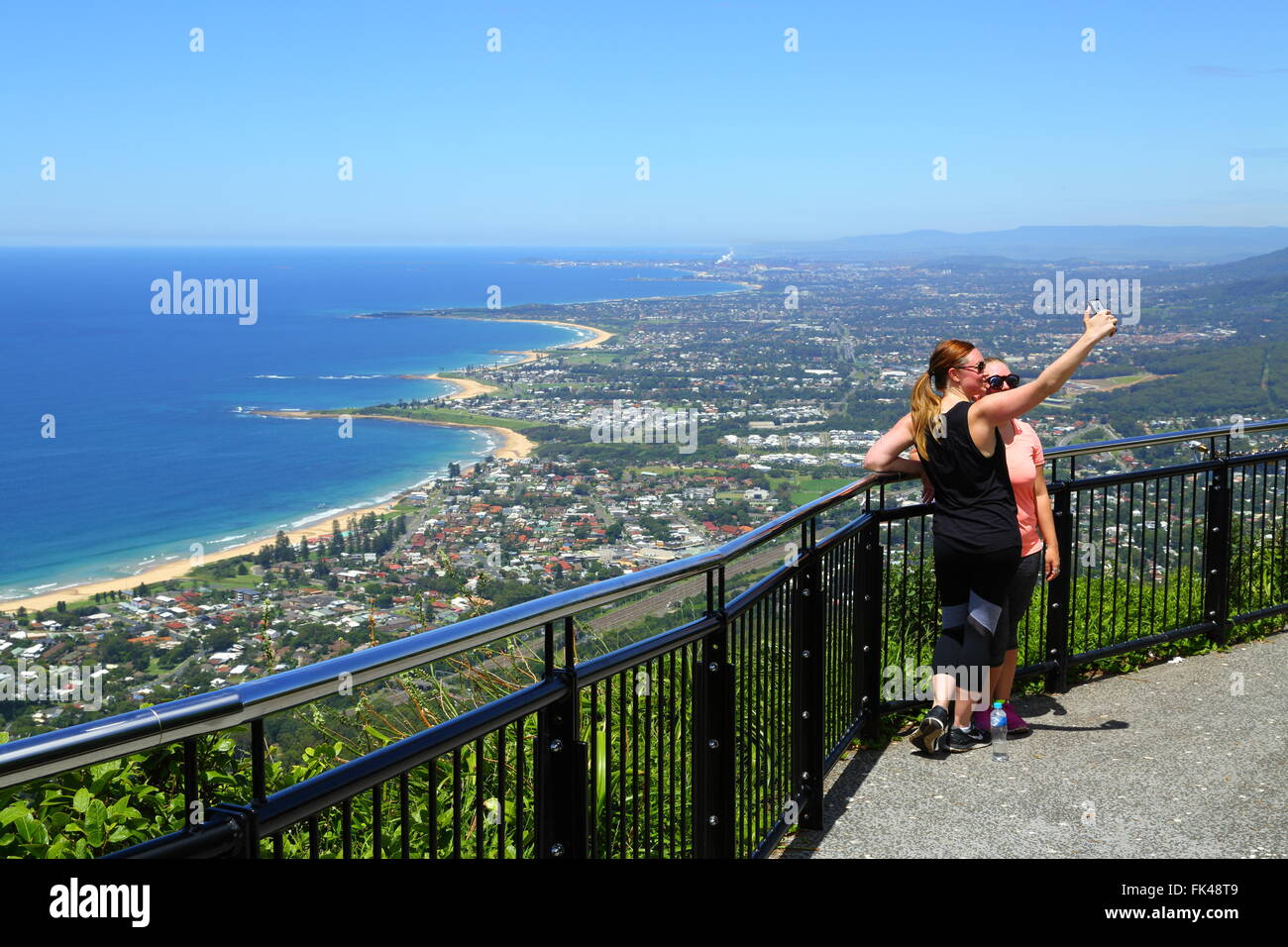 Zwei Damen in ihren Zwanzigern nehmen ein Selbstporträt mit Blick auf die Illawarra Coast und Wollongong von Sublime Point Lookout in New South Wales. Stockfoto