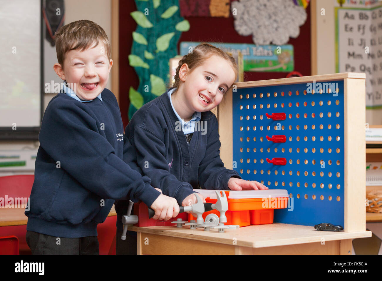 Schülerinnen und Schüler in Schuluniform in einer Grundschule im Vereinigten Königreich mit Spielzeug spielen Handwerkzeuge. Stockfoto