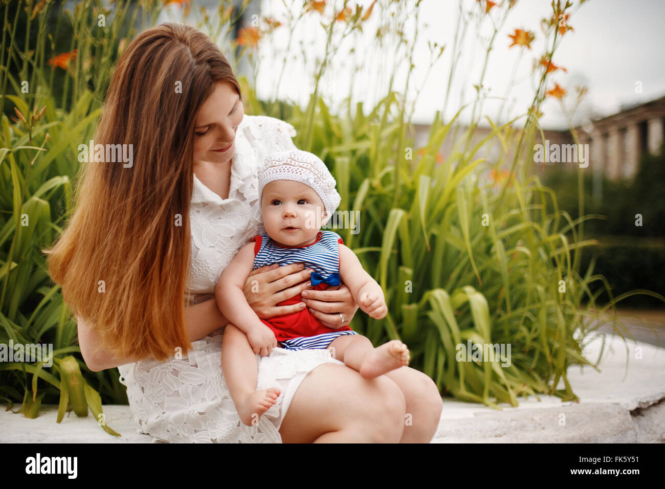 Niedliche glücklich Kleinkind auf liebevolle Mutter Knien sitzen und Lächeln auf den Lippen. Familienspaß. Selektiven Fokus. Stockfoto