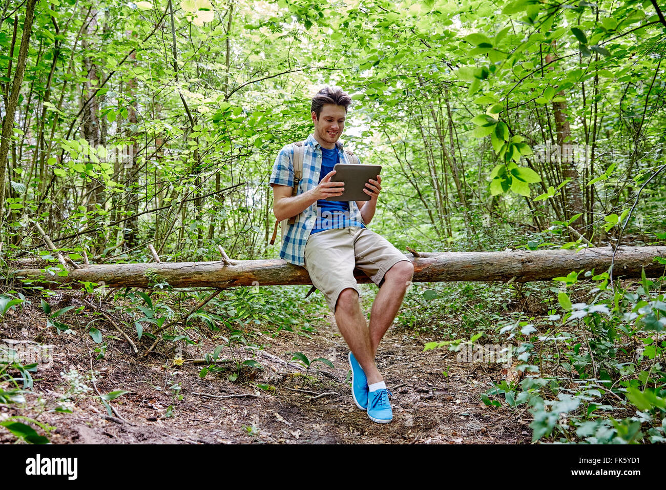 glücklicher Mann mit Rucksack und Tablet pc in Wäldern Stockfoto