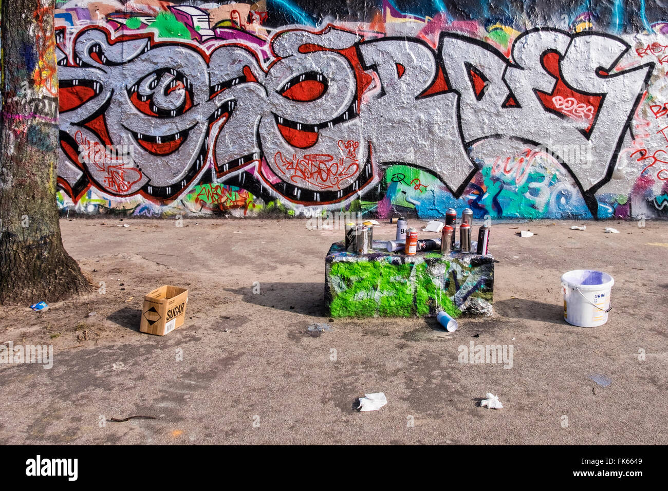 Graffiti auf der Berliner Mauer und Spraydosen von Sprühfarbe links von Straßenkünstlern, Mauerpark, Berlin Stockfoto