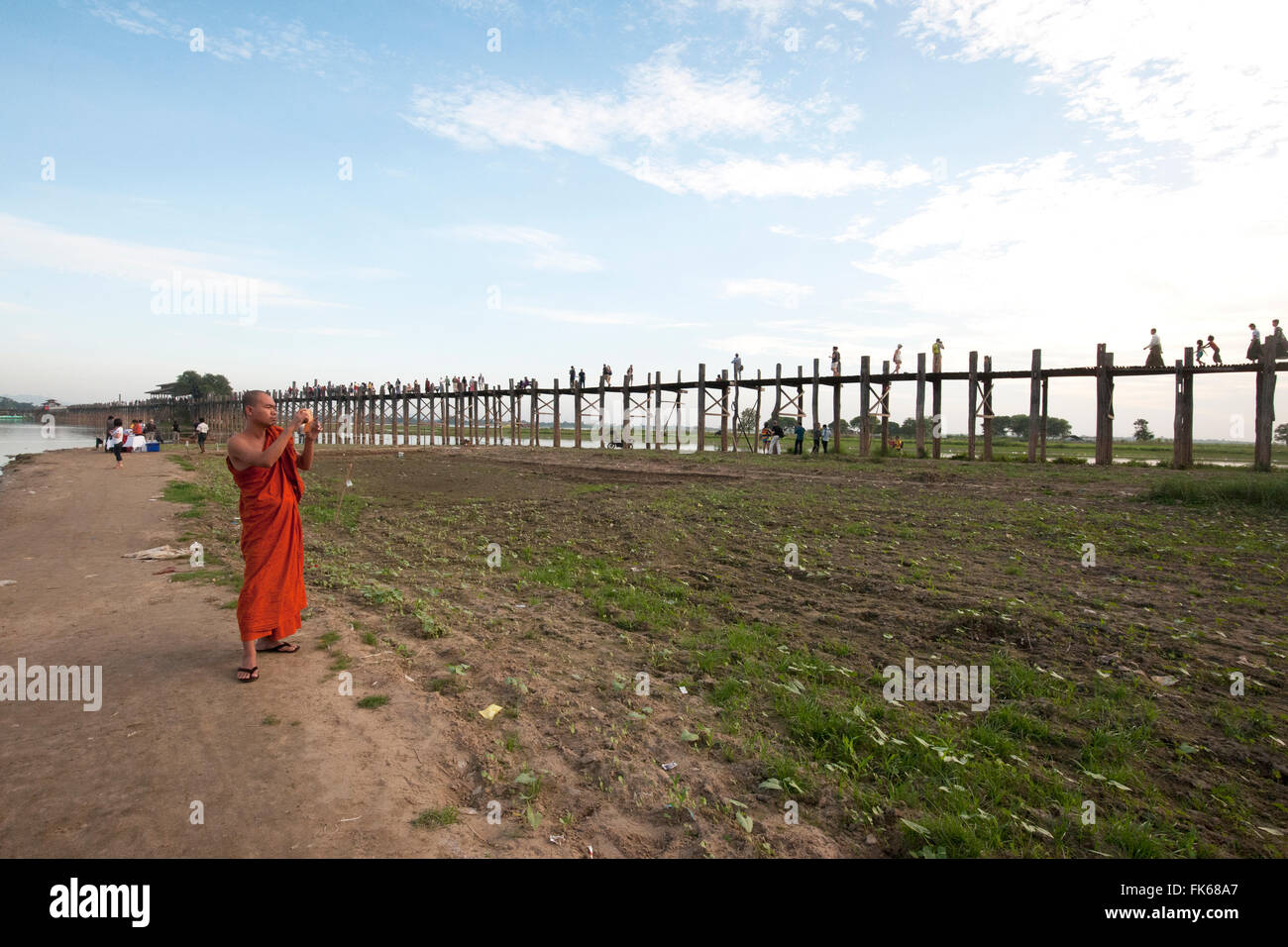 Orange gekleidet Mönch fotografieren Menschen Kreuzung U Bein Brücke, unterstützt von 984 Teak Beiträge über Thaumthaman Lake, Mandalay Stockfoto