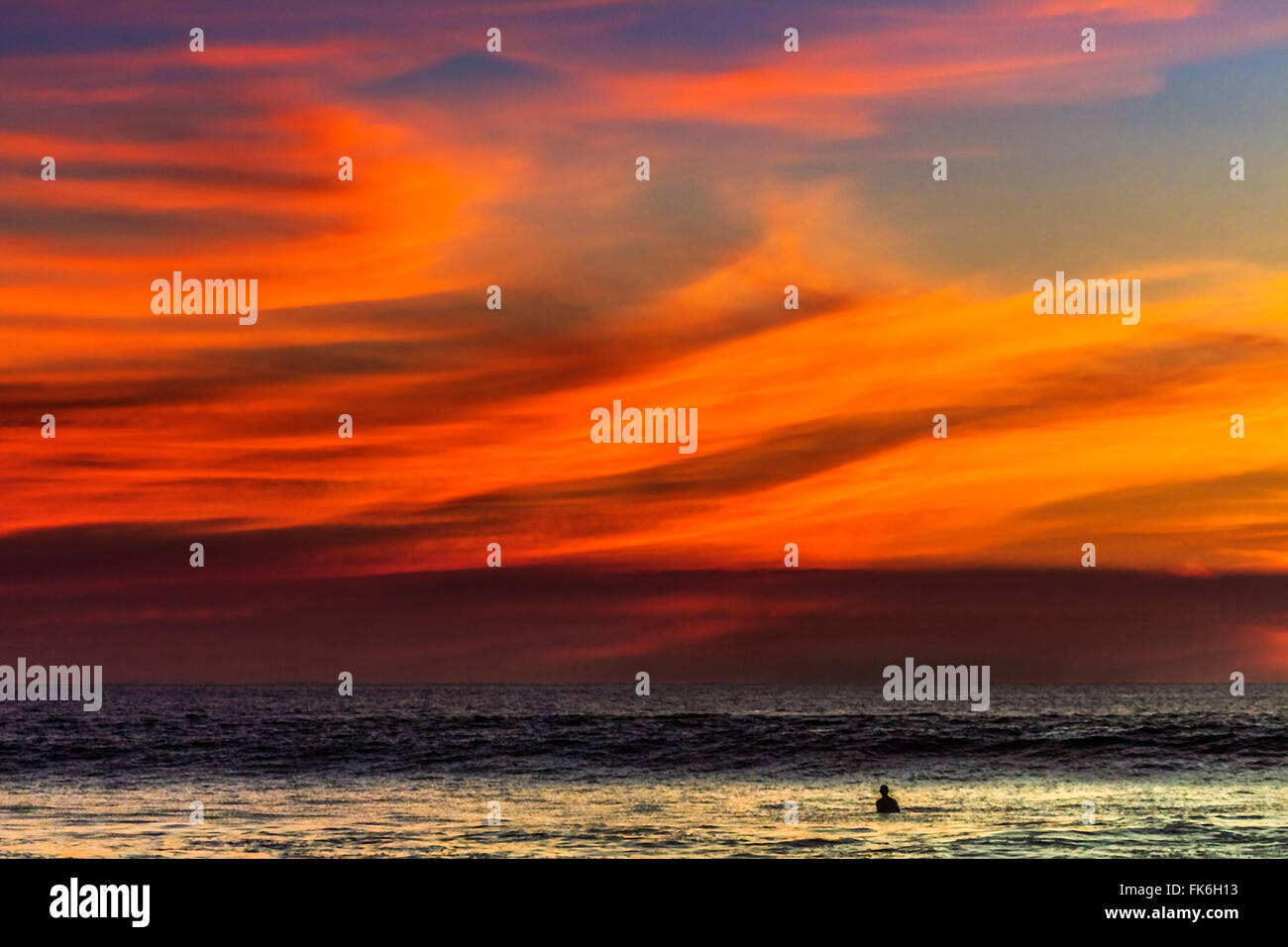 Einsamer Surfer und Sonnenuntergang Wolken vor Playa Hermosa Surf Beach, Nicoya Halbinsel, Santa Teresa, Puntarenas, Costa Rica Stockfoto