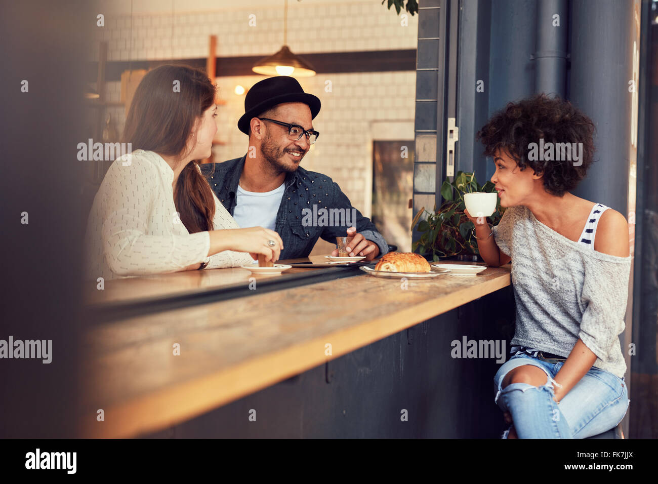 Glückliche junge Menschen in einem Café sitzen und miteinander zu reden. Gruppe von jungen Freunden kommunizieren und Spaß in einem Kaffee Stockfoto