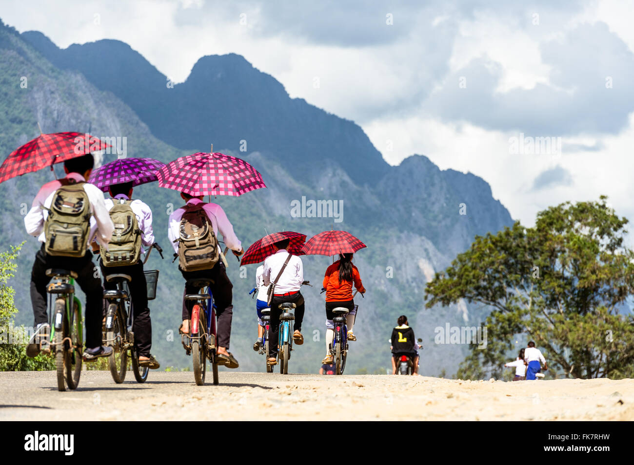 Asien. Süd-Ost-Asien. Laos. Provinz von Vang Vieng. Kinder verlassen die Schule mit dem Fahrrad. Stockfoto