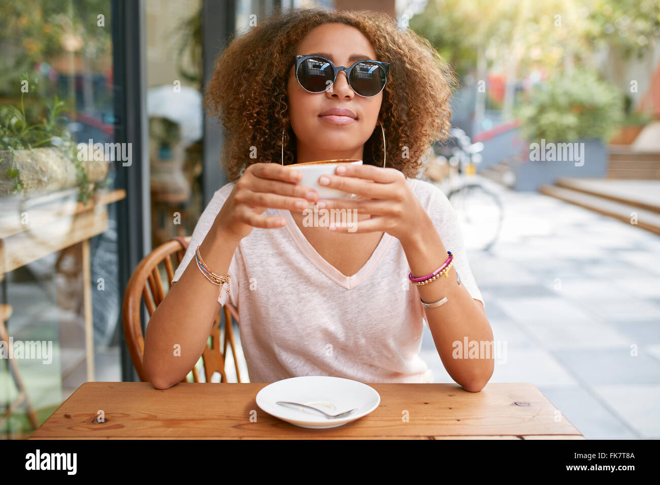 Porträt der hübsche junge Frau sitzt am Straßencafé Kaffee trinken. Attraktive Afrikanerin mit einer Tasse Kaffee. Stockfoto