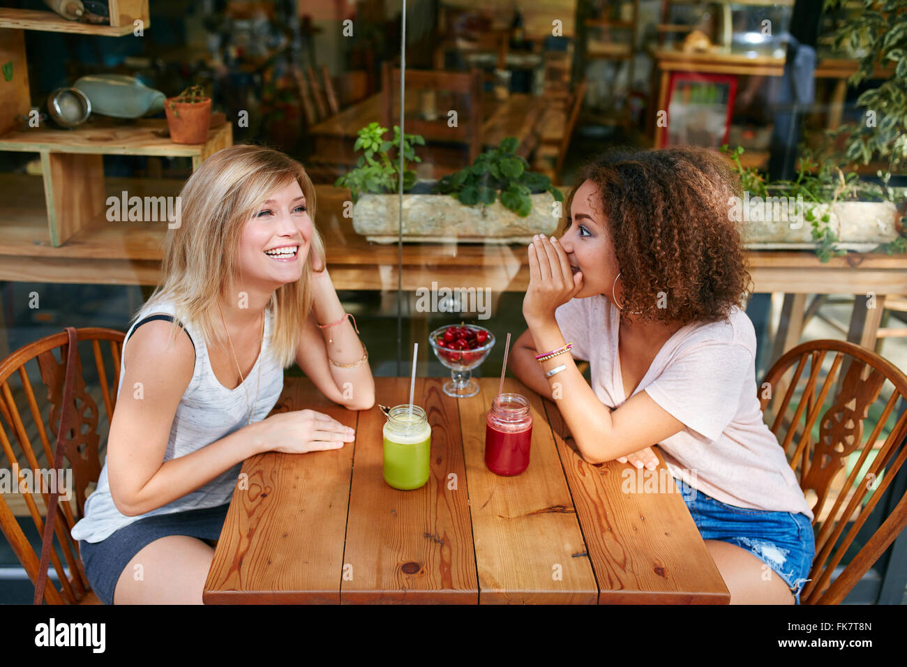 Junge Freundinnen mit privaten Klatsch im Straßencafé. Zwei junge Frauen tratschen und Flüstern im Freien in einem Coffee-shop Stockfoto