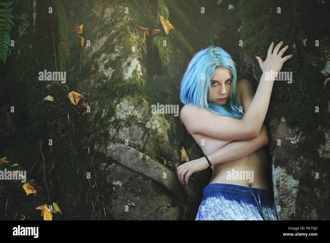 Schöne Frau mit blaugrünen Haaren im dunklen Wald. Fantasie und surreal Stockfoto
