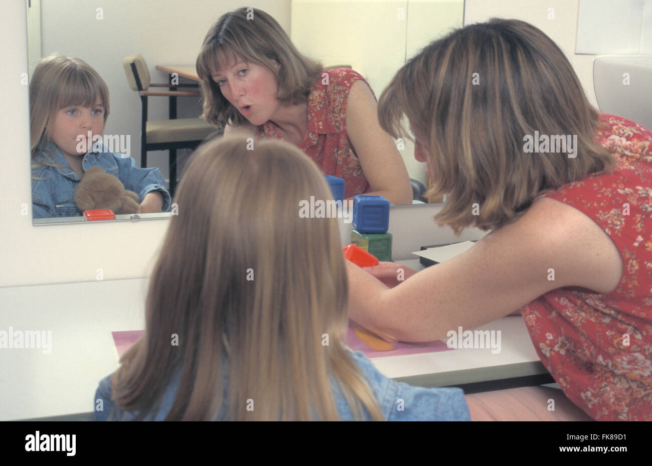 Logopädin und Mädchen arbeiten vor Spiegel Stockfoto