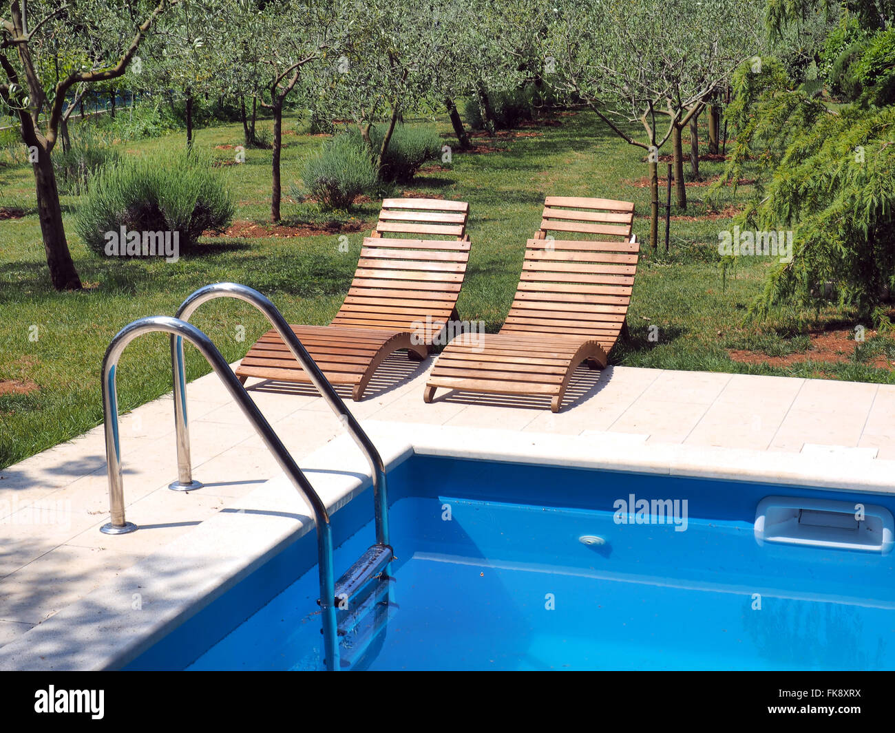 Luxus-Schwimmbad mit grünem Rasen und Stühle Stockfoto