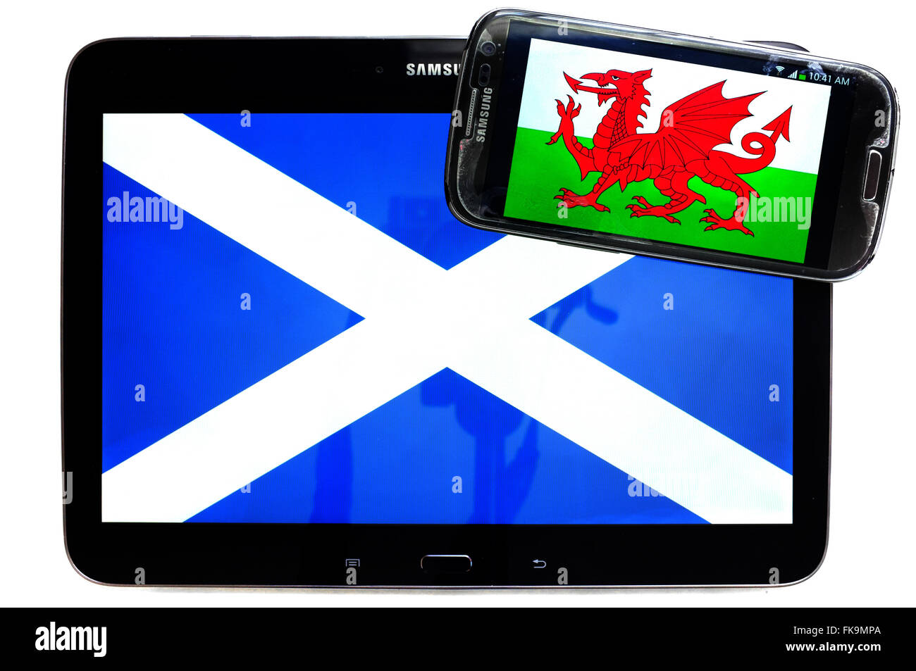 Ein Tablet mit der schottischen Flagge drauf und ein Smartphone mit dem walisischen Fahne auf weißem Hintergrund. Stockfoto