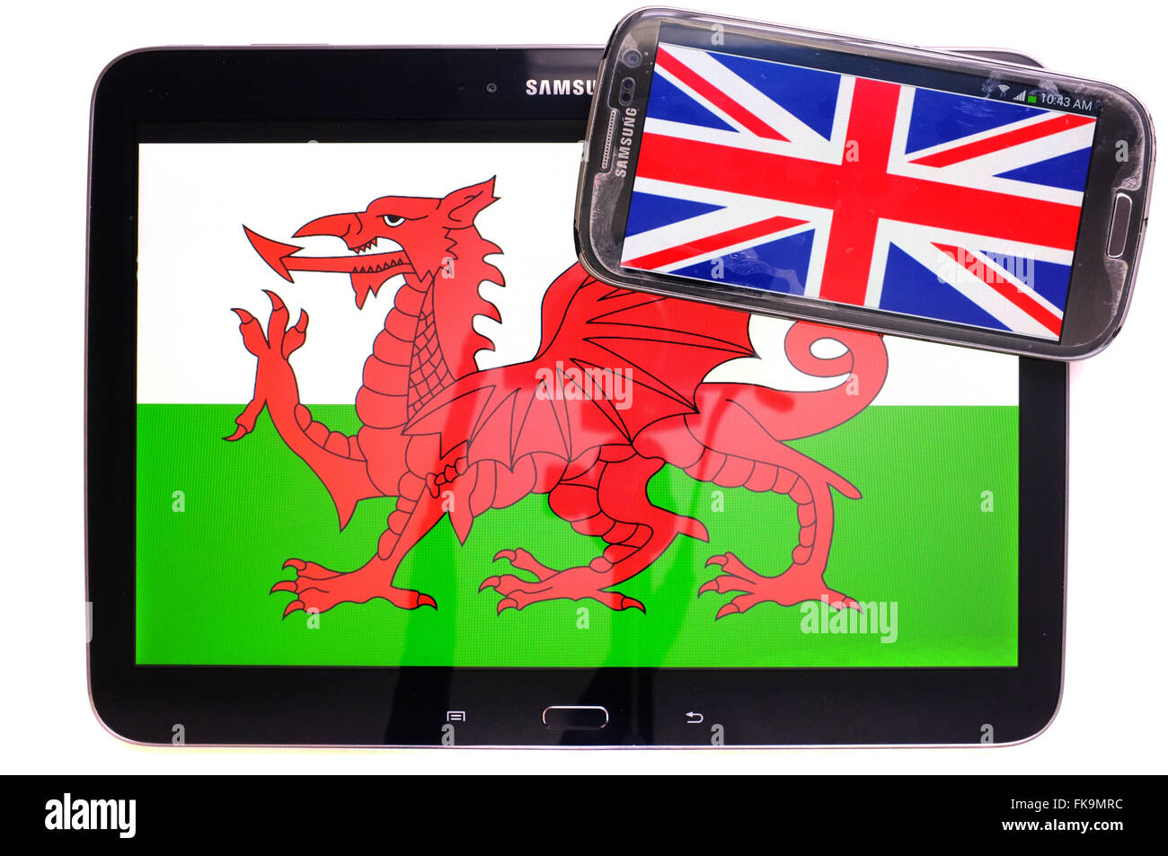 Ein Tablet mit dem walisischen Fahne drauf und ein Smartphone mit dem Union Jack vor weißem Hintergrund fotografiert. Stockfoto