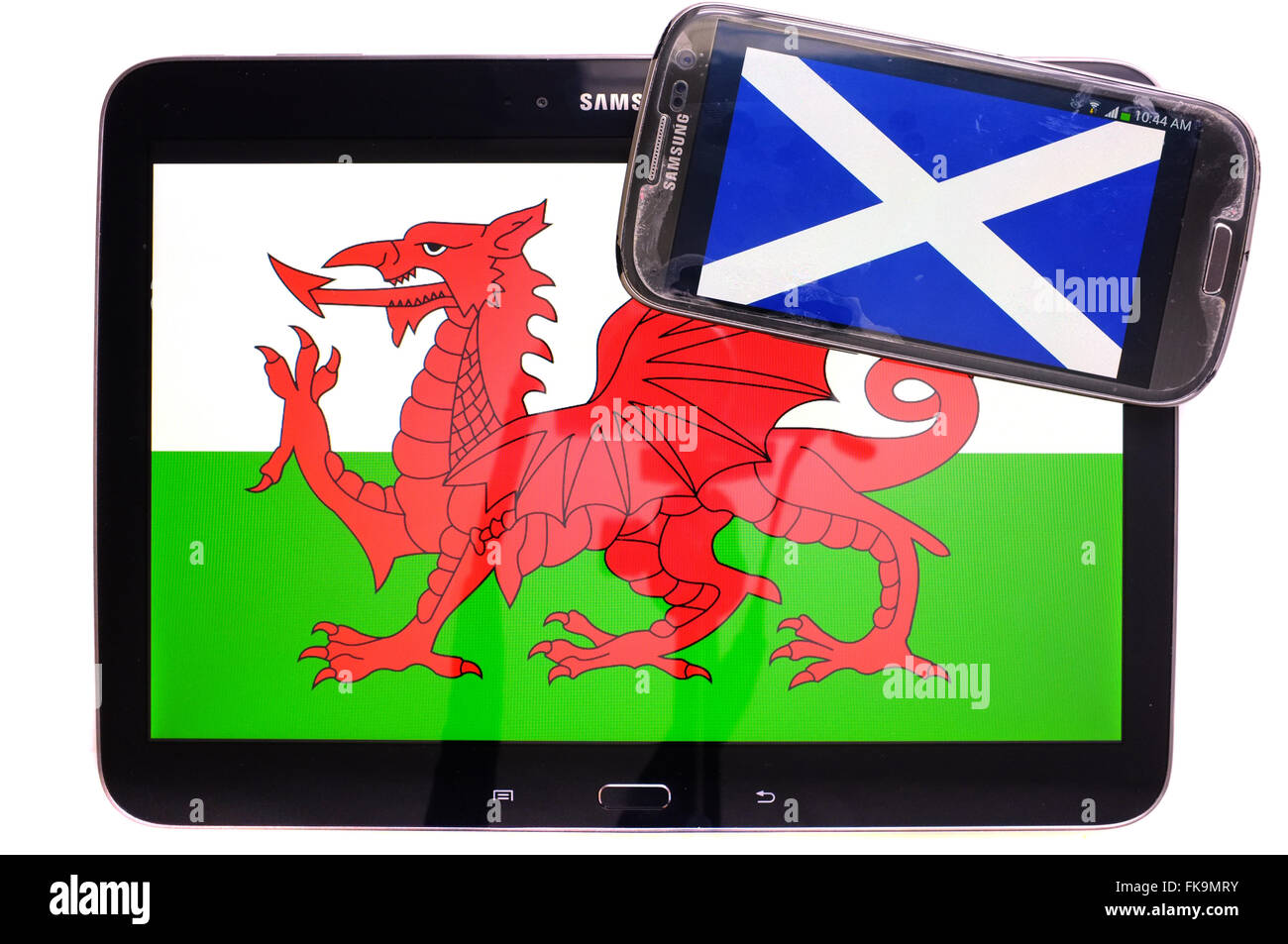 Ein Tablet mit dem walisischen Fahne drauf und ein Smartphone mit der schottischen Flagge vor einem weißen Hintergrund fotografiert. Stockfoto