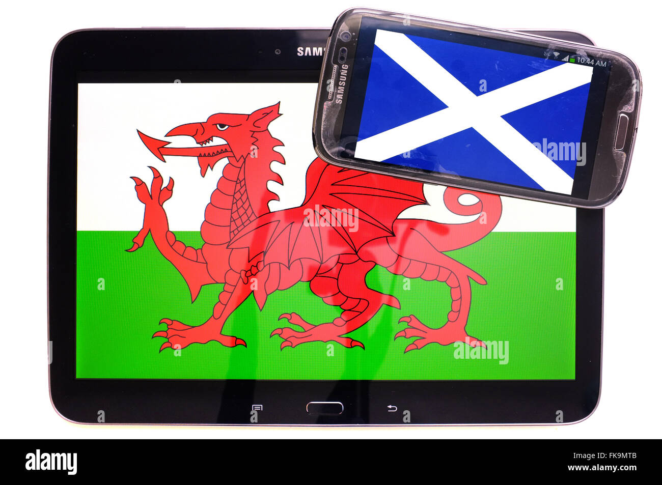 Ein Tablet mit dem walisischen Fahne drauf und ein Smartphone mit der schottischen Flagge auf weißem Hintergrund fotografiert. Stockfoto