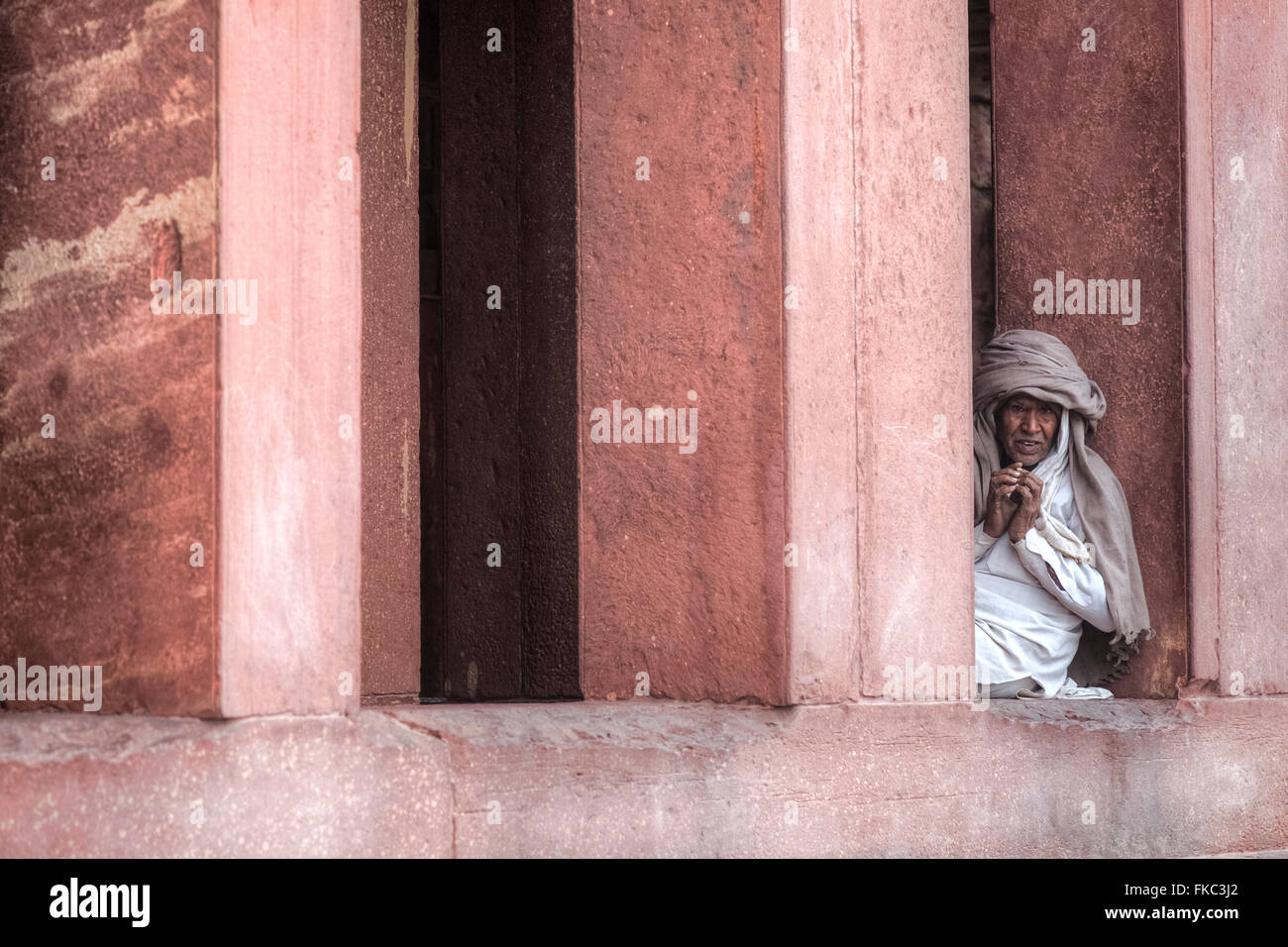 Mann sitzt zwischen den Säulen in Fatehpur Sikri; Agra; Uttar Pradesh; Indien; Stockfoto