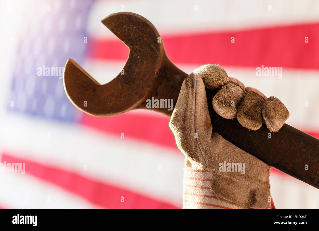 Manuelle Arbeiter Hand Holding Schraubenschlüssel mit amerikanischen Flagge im Hintergrund Stockfoto