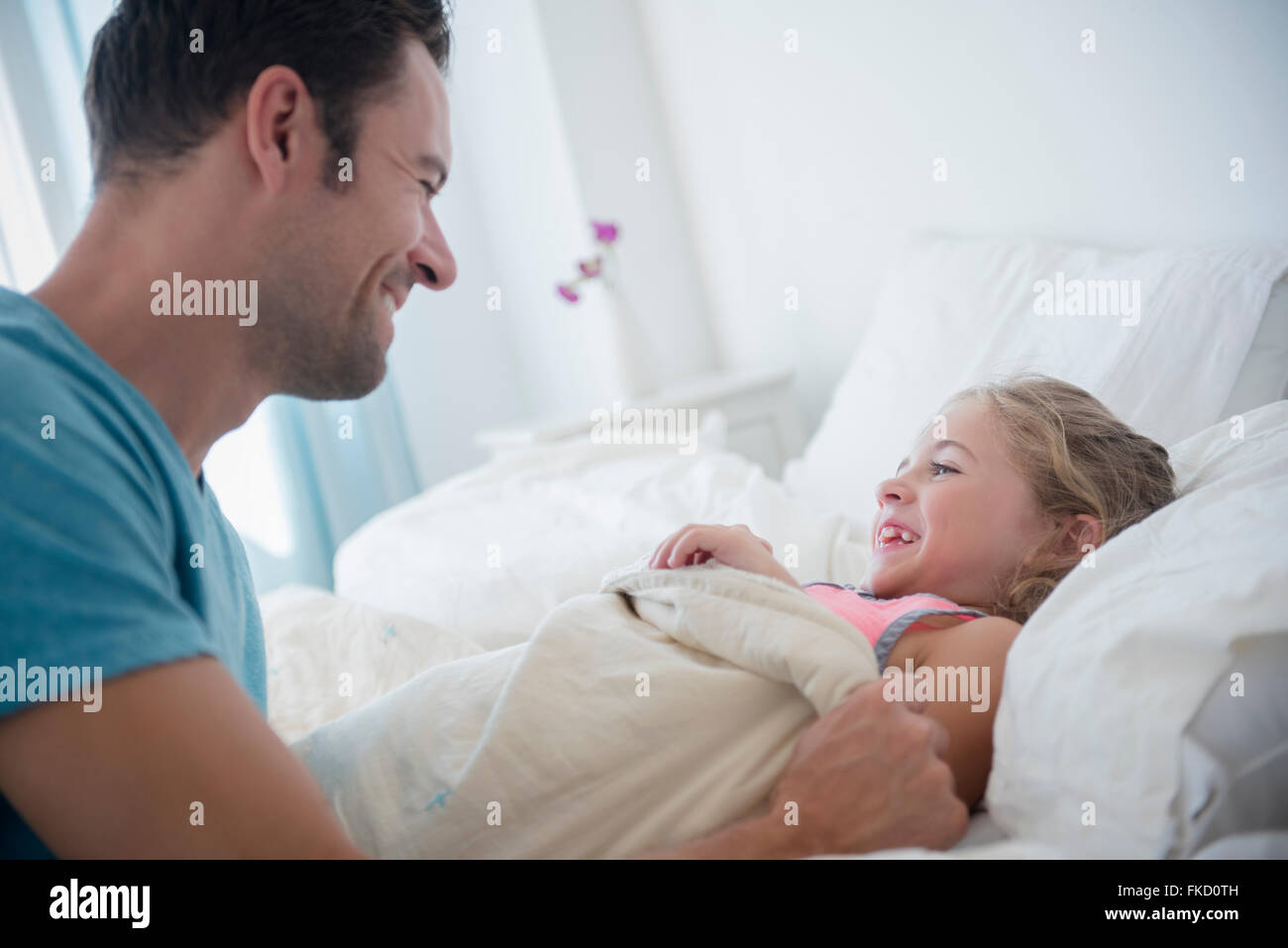 Vater stopfte Tochter im Bett (6-7) Stockfoto