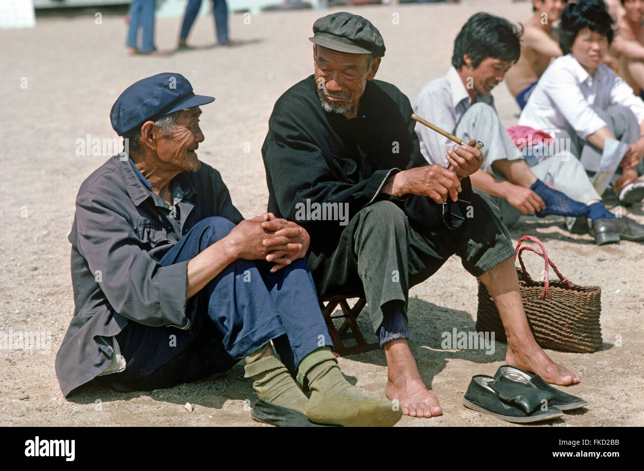 Einige alte chinesische Männer unter der Sonne am Strand von Qingdao, Provinz Shandong, China Stockfoto