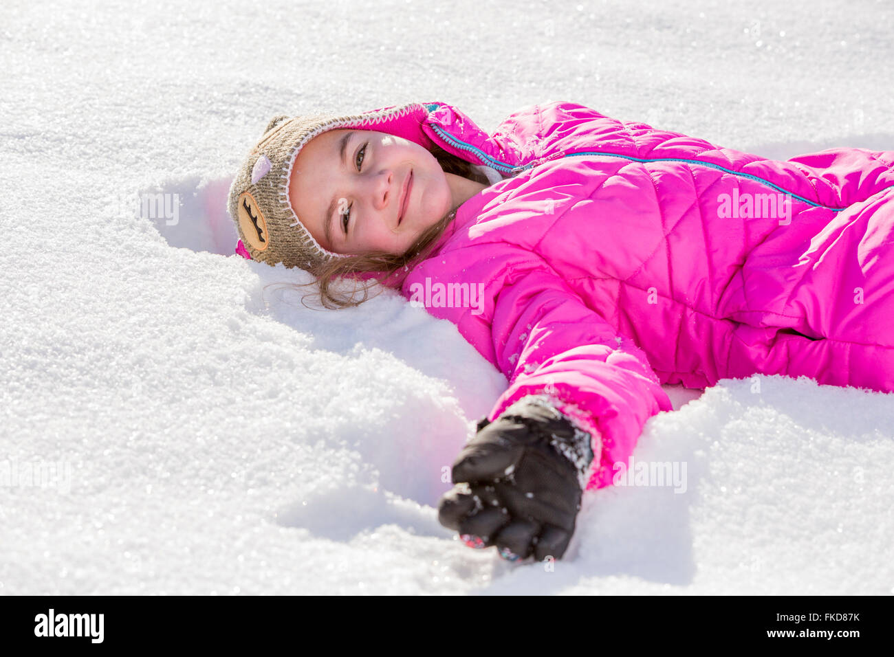 Mädchen (10-11) in rosa Jacke im Schnee liegend Stockfoto