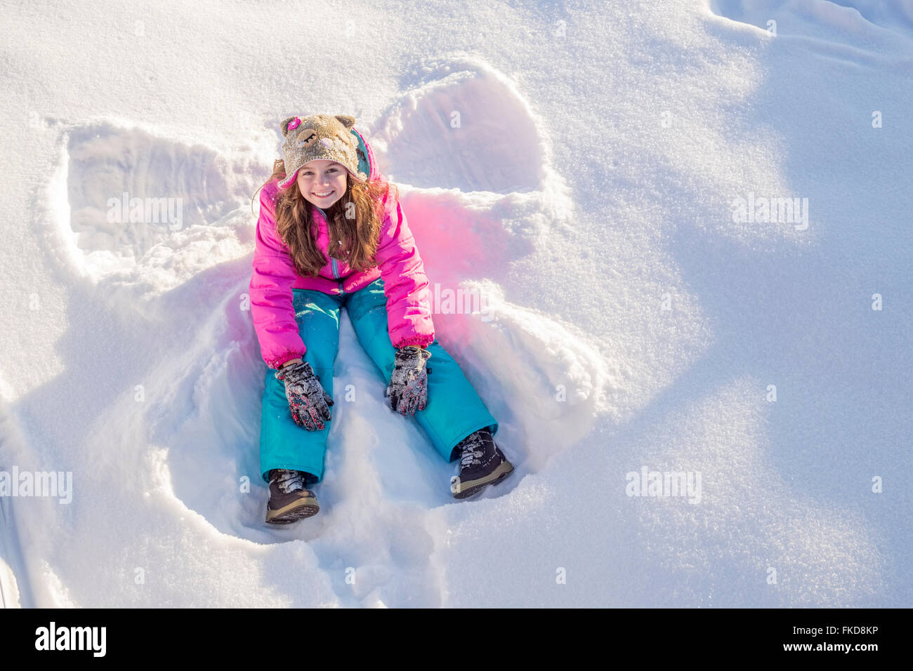 Mädchen (10-11) in rosa Jacke sitzen im Schnee Stockfoto