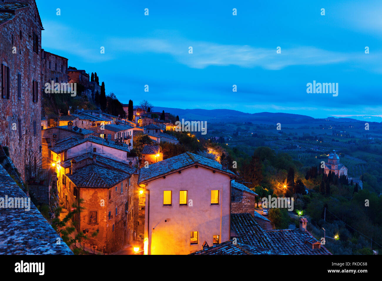Montepulciano, Häuser beleuchtet auf Felsen unter bewölktem Himmel Stockfoto