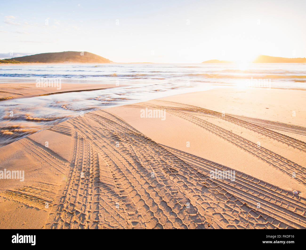 Reifenspuren am Strand bei Sonnenuntergang Stockfoto