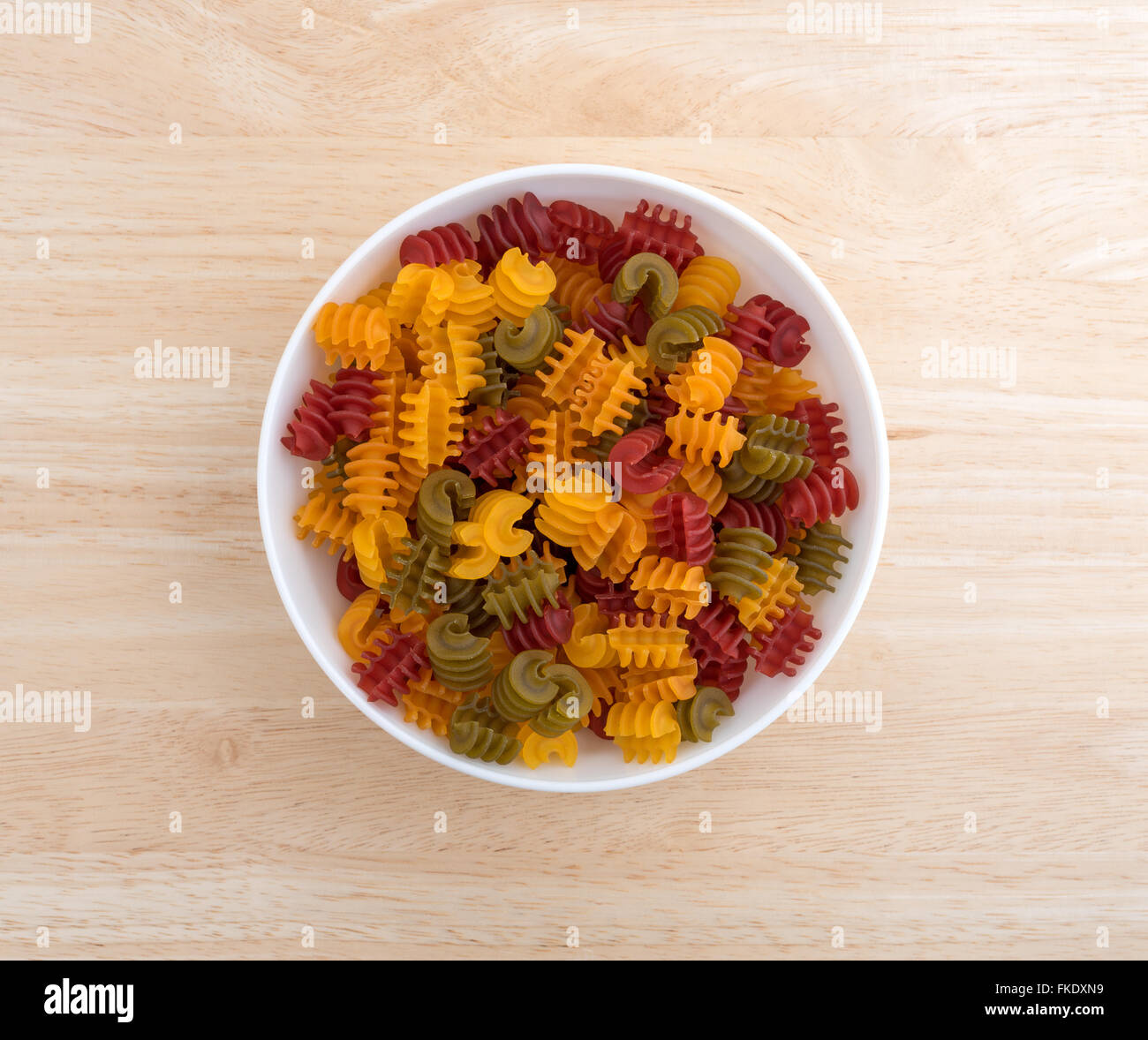 Draufsicht auf eine Portion Gluten freie Mais Gemüse Radiatore Nudeln in einer weißen Schüssel auf einer hölzernen Tischplatte mit natürlichen beleuchtet Stockfoto