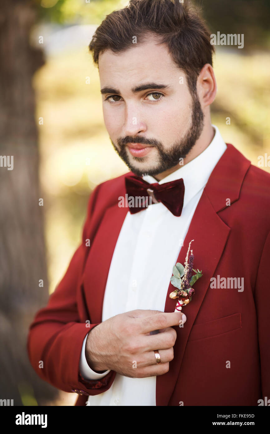 Porträt des Bräutigams im roten Anzug mit Fliege, Bart und Schnurrbart. Stockfoto