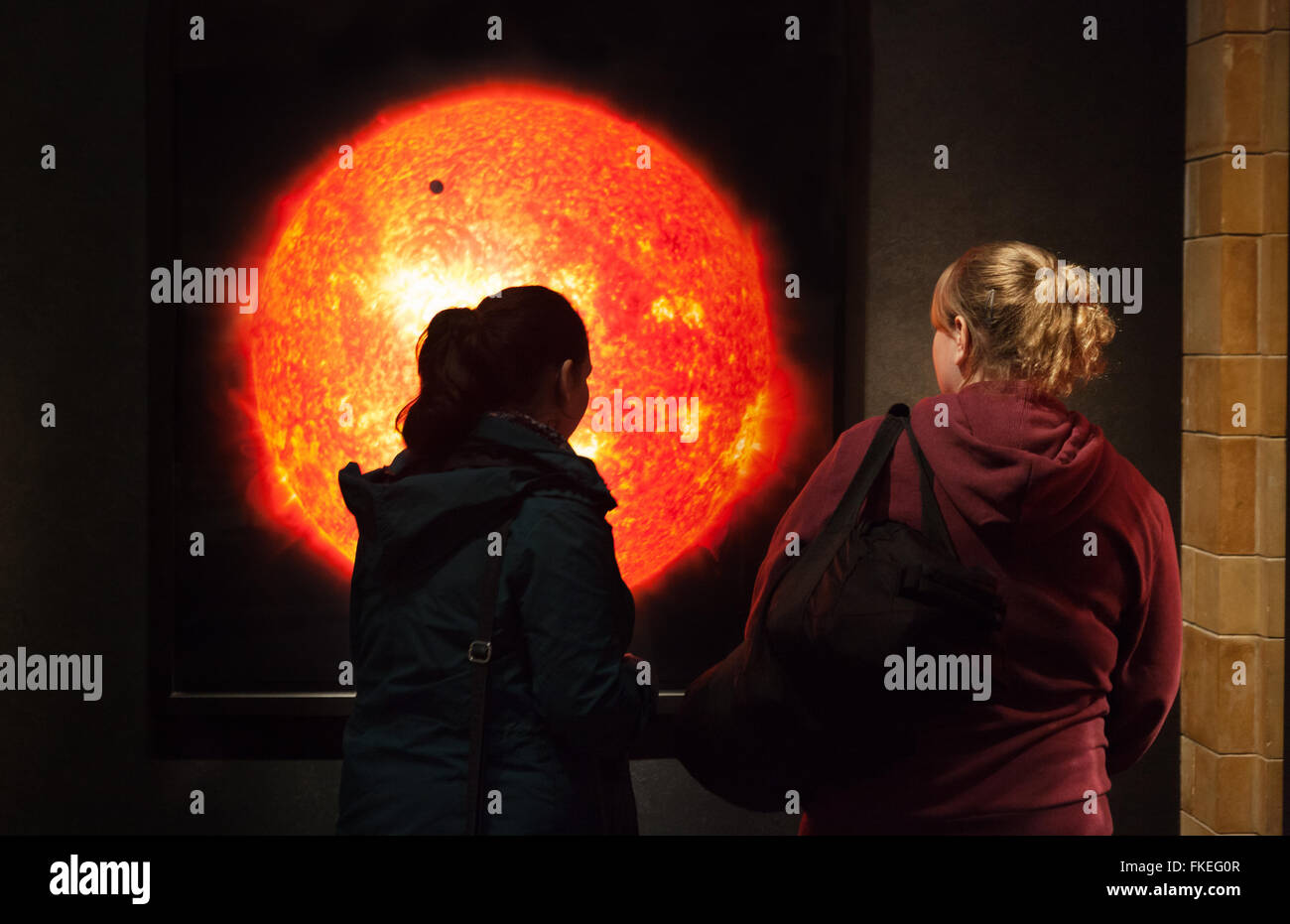 Zwei Frauen, die mit Blick auf ein Bild der Sonne durch Michael Benson, "Anderswelten"-Ausstellung, London UK Stockfoto