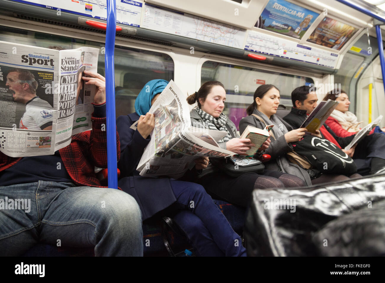 Passagiere, die lesen Bücher und Zeitungen in einem Londoner u-Bahn Wagen, London UK Stockfoto