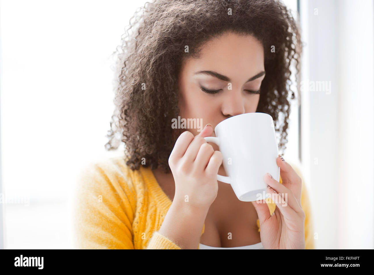 Angenehme Mulatte Frau trinkt Tee Stockfoto