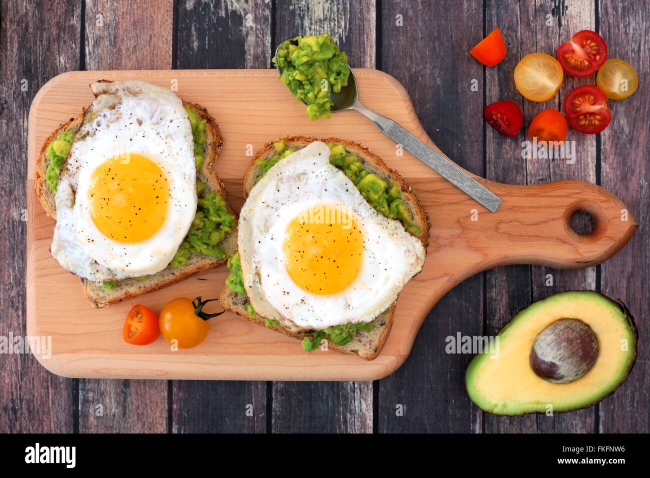 Avocado, Ei belegte Brötchen auf Vollkornbrot mit Tomaten auf Paddel Board mit rustikalen Holztisch Stockfoto