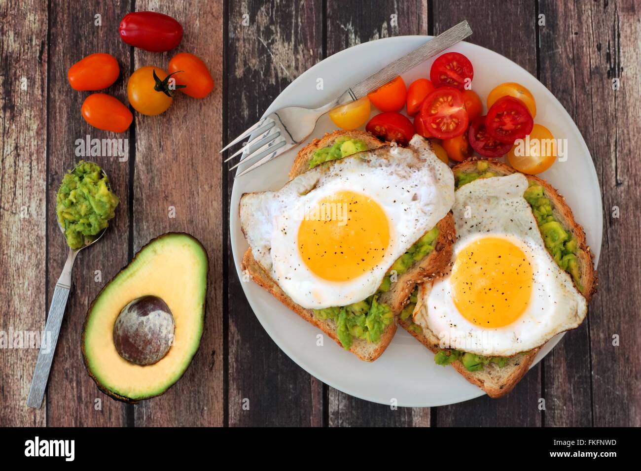 Gesunden Avocado, Ei belegte Brötchen auf einem Teller mit Cherry-Tomaten auf einem rustikalen Holz Hintergrund Stockfoto