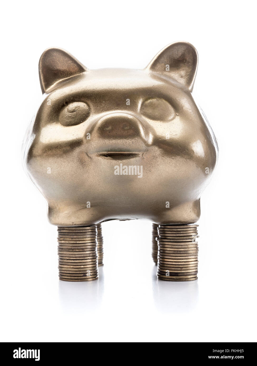 Goldene Sparschwein stehend auf Haufen von Münzen auf weißem Hintergrund Stockfoto