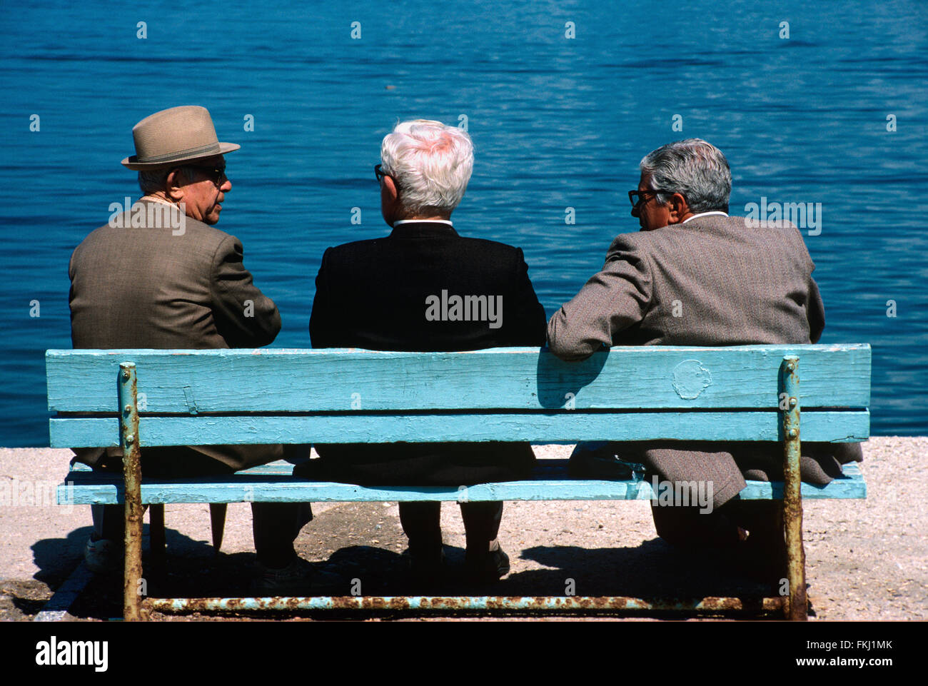 Drei ältere türkische Männer oder Türken im Chat auf blau Park Bench, Kusasasi, Türkei Stockfoto
