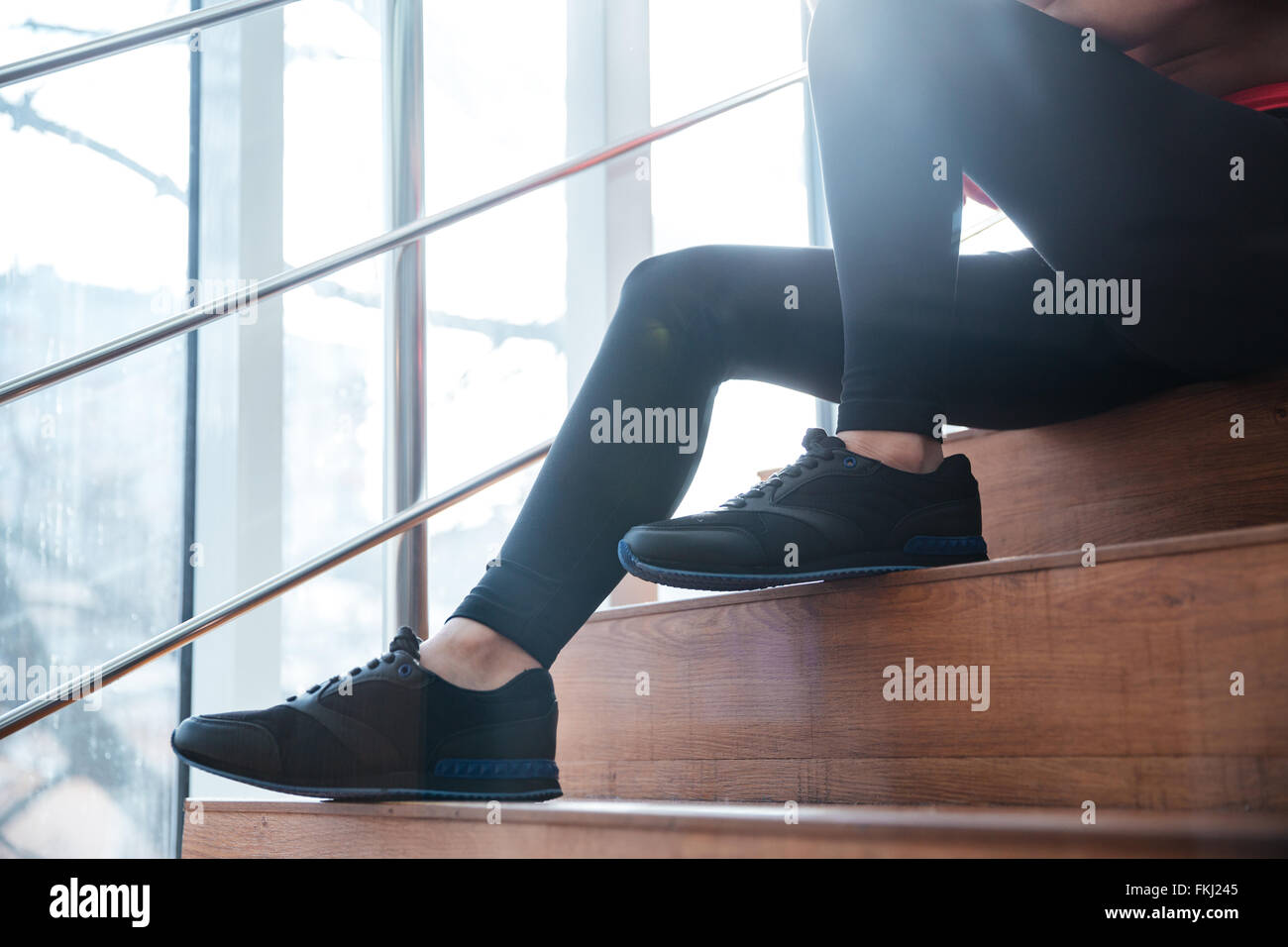 Nahaufnahme der Beine in schwarzen Leggins und Turnschuhen der jungen  Sportlerin, die sitzt auf der Treppe Stockfotografie - Alamy