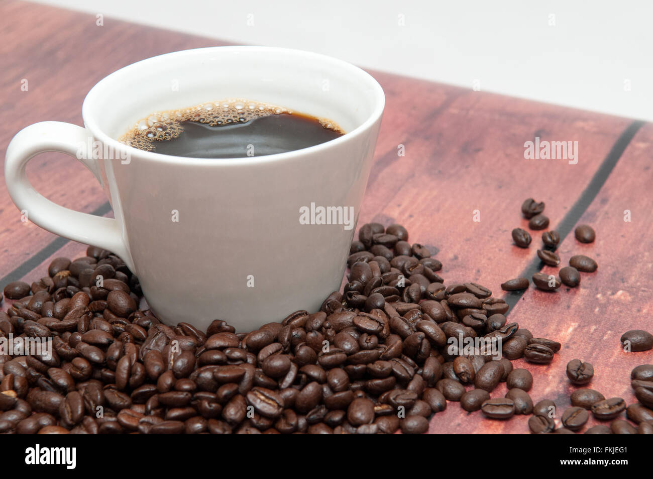 Stark gewürzte Kaffee Bohnen in eine schlichte weiße Tasse Stockfoto