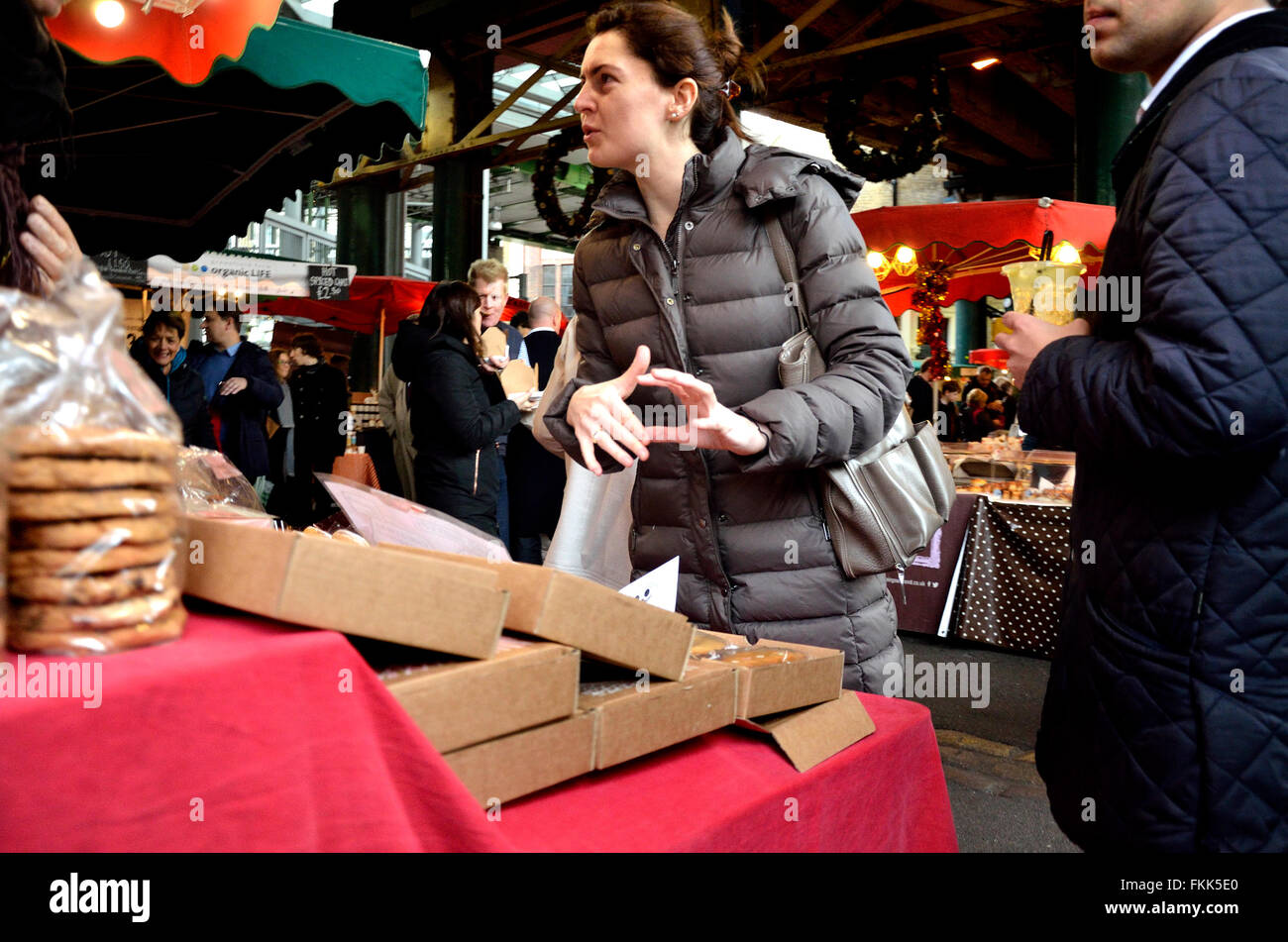 London, England, Vereinigtes Königreich. Borough Market, Southwark. Frau im Gespräch mit einem Standbesitzer Stockfoto