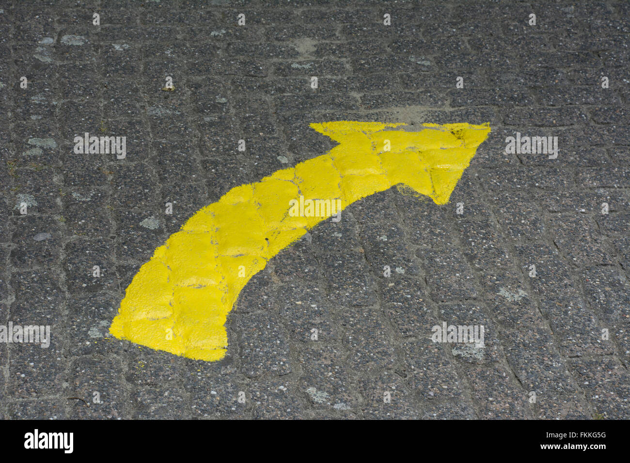 Gebogener gelber Pfeil auf asphaltierten Straße. Stockfoto